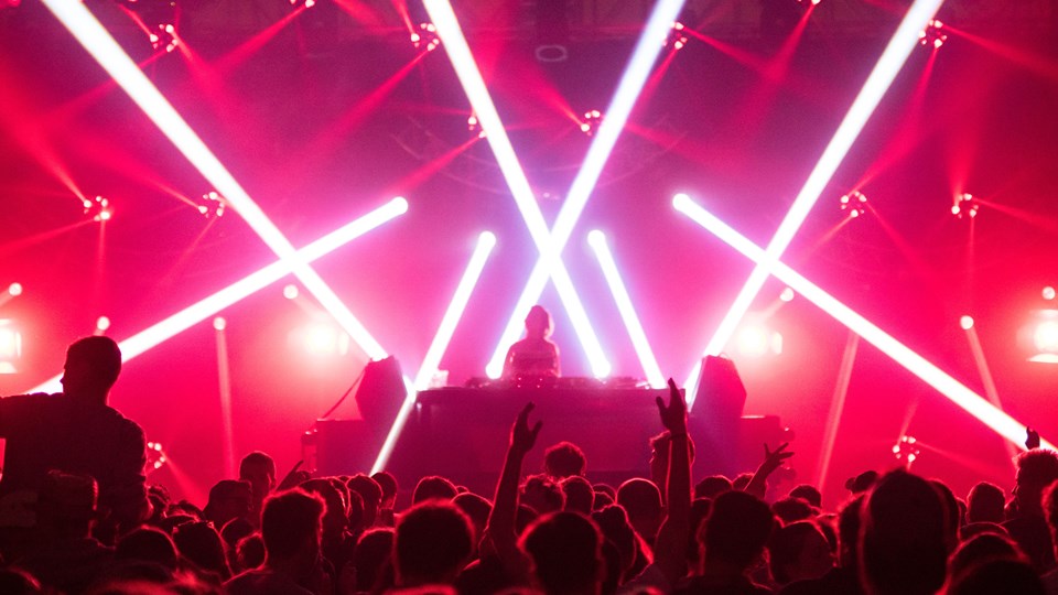 Människor som dansar på ett dansgolv i ett rum fyllt av strålkastare och rött ljus
