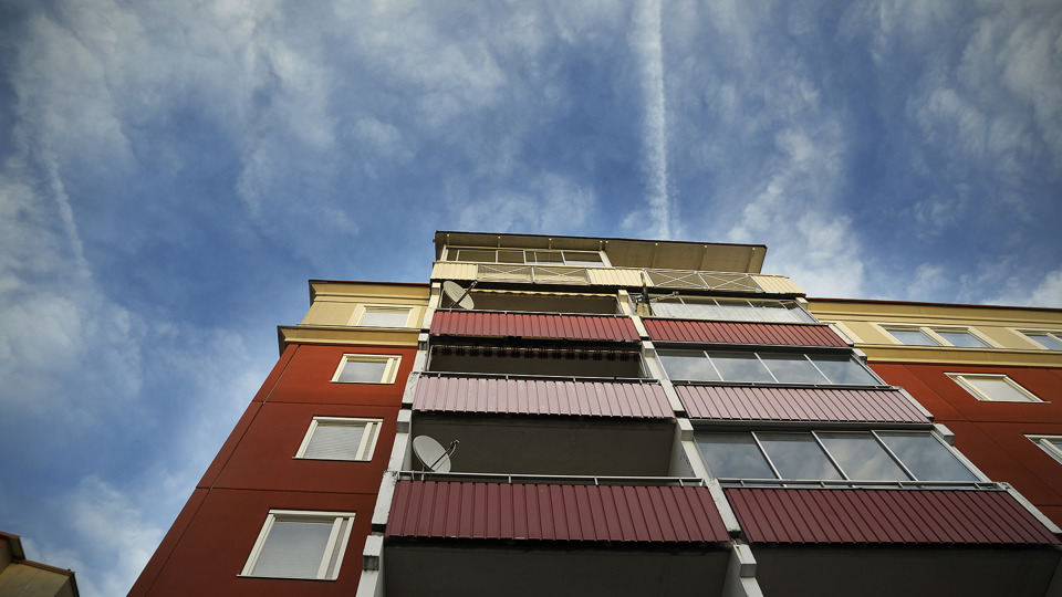 Blå himmel med moln med rödaktig fasad med flerfamiljshus.