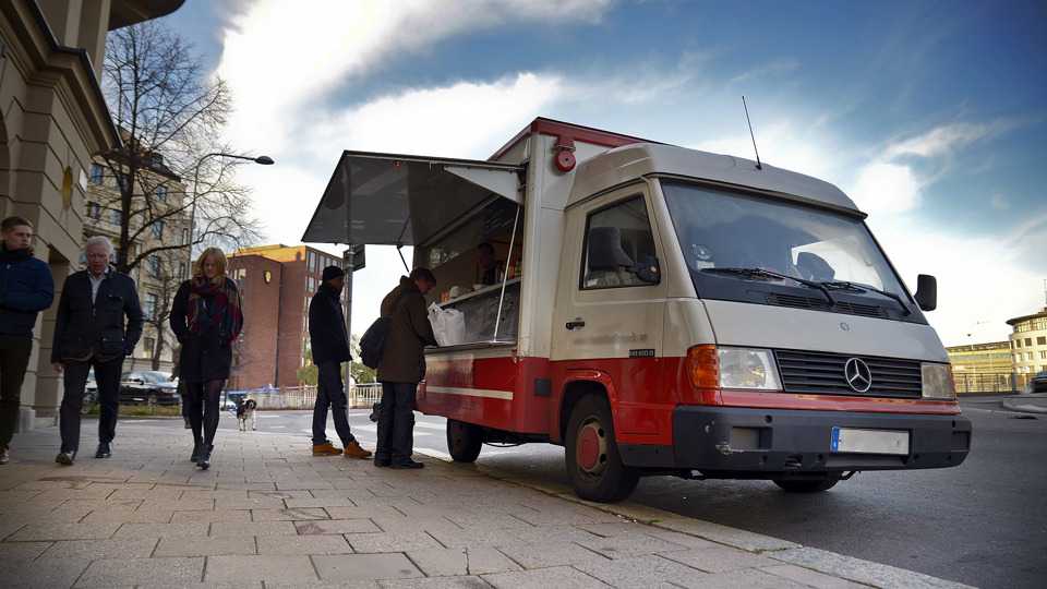 Människor står utanför en foodtruck.